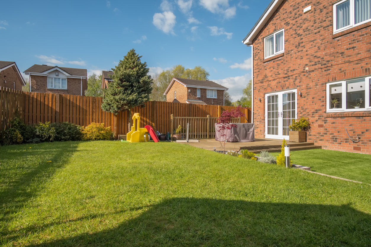 A newly completed and replanted landscaped garden with mixer of artificial and natural sown grass, new borders planted, a new decking patio and garden ornaments surrounded by new erected wooden fencing.