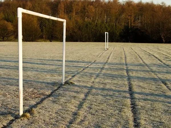 Sports pitch with goal posts. Frosted grass.